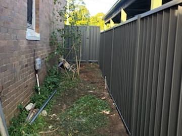 Charcoal Colorbond privacy fence running away from a brick house wall
