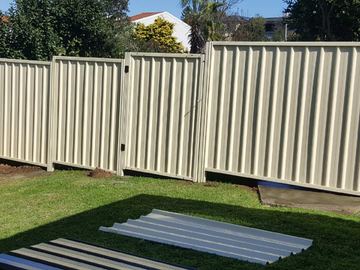 Short cream Colorbond privacy fence with a matching pedestrian gate on a lawn
