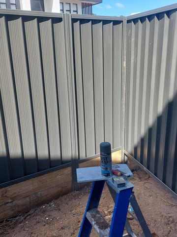 Close view of dark Colorbond privacy sheets with a sawhorse at the base
