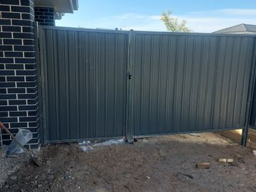 Charcoal Colorbond double gate set in a matching privacy fence on a bare yard