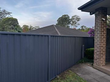 Charcoal Colorbond privacy fence meeting a brick verandah pier on the street front