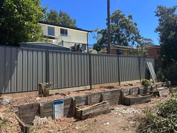 Mid grey Colorbond privacy fence above empty timber garden beds