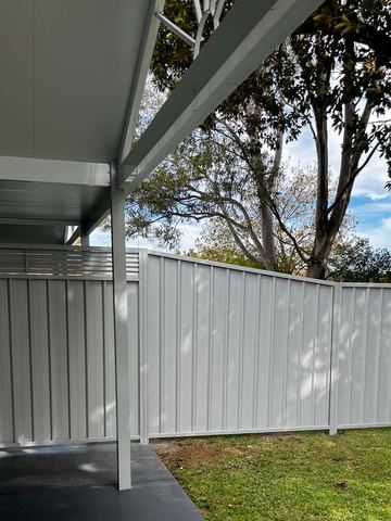 White Colorbond privacy fence seen from under an open patio roof