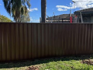 Close view of brown Colorbond privacy sheets along a backyard boundary