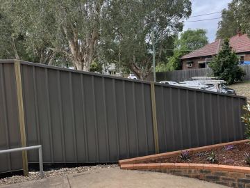 Charcoal Colorbond privacy fence stepping down a sloping street boundary