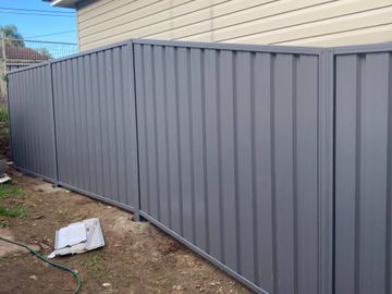 Mid grey Colorbond privacy fence turning a corner on a bare residential block
