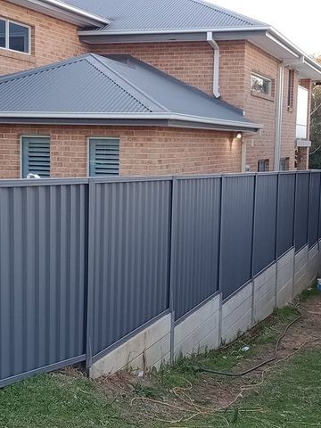 Charcoal Colorbond privacy fence across the front of a house with a covered barbecue