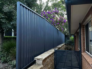 Navy Colorbond privacy fence along a house with a matching slat pedestrian gate