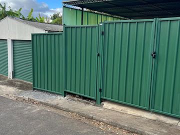 Green Colorbond double gate in front of roller doors
