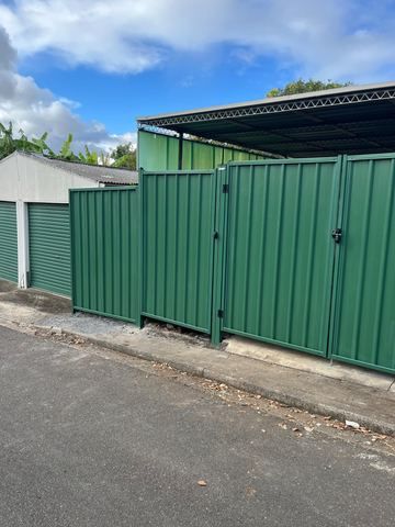 Green Colorbond double gate in front of roller doors