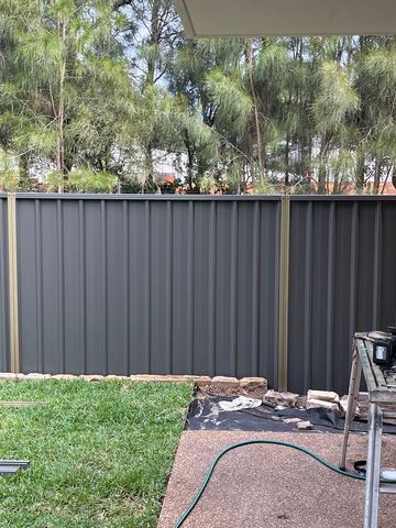 Charcoal Colorbond privacy sheets and posts on a grassed boundary