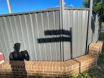Charcoal Colorbond privacy fence sitting on a brick corner plinth