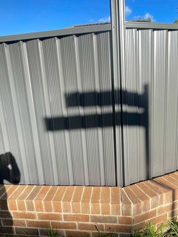 Charcoal Colorbond privacy fence sitting on a brick corner plinth