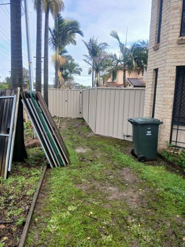 Cream Colorbond privacy fence turning a corner across a grassed backyard