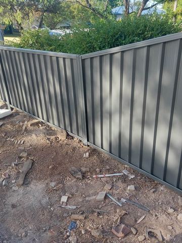 Charcoal Colorbond privacy fence turning an inside corner on a dirt yard