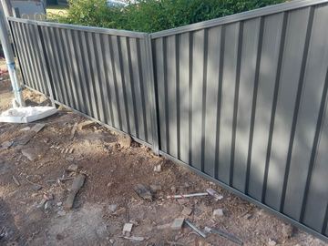 Charcoal Colorbond privacy fence turning an inside corner on a dirt yard
