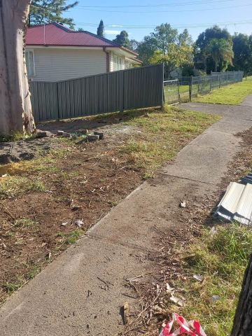 Light grey Colorbond privacy fence along a concrete path with leftover sheeting