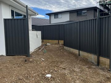 Black Colorbond privacy fence and matching pedestrian gate on a new house block