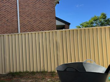 Cream Colorbond privacy fence with a fire pit in the foreground