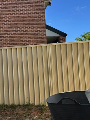 Cream Colorbond privacy fence with a fire pit in the foreground
