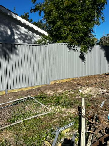 Light grey Colorbond privacy fence on a dirt yard with a leftover mesh panel