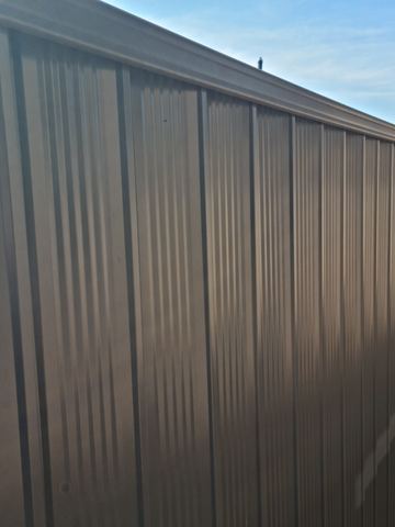 Close view of dark bronze Colorbond privacy sheets along a boundary