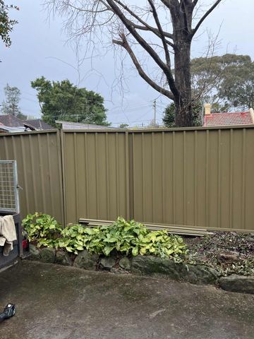 Olive Colorbond privacy fence beside a leafy garden bed
