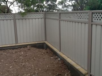 Light grey Colorbond privacy fence with a matching lattice topper turning a corner on a new block