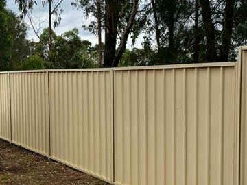 The scene shows a mid grey corrugated steel fence where sleepers form the base.