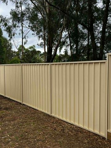The scene shows a mid grey corrugated steel fence where sleepers form the base.
