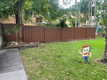 The scene shows a mid grey corrugated steel fence where garden beds sit at the base.