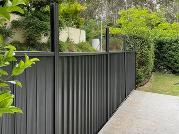 Charcoal Colorbond privacy fence turning a corner beside a garden path