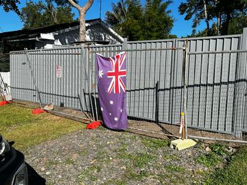 Temporary mesh fence panel on a dirt yard with an Australian flag hanging from it