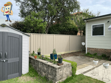 Cream Colorbond privacy fence beside a garden shed and a raised garden bed