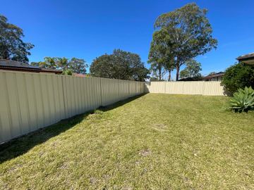 Long cream Colorbond privacy fence stretching across an open lawn