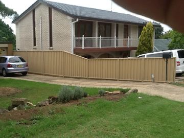 The scene shows a brown corrugated steel fence where sleepers form the base.