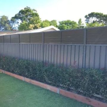 Mid grey Colorbond privacy fence running behind a clipped hedge on a lawn