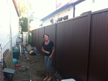 Bronze Colorbond privacy fence in a side yard with a person standing beside it