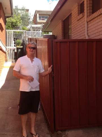 Installed red Colorbond sheets forming a privacy boundary.