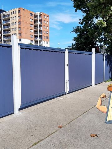 Blue Colorbond sliding driveway gate on a concrete driveway in front of apartments
