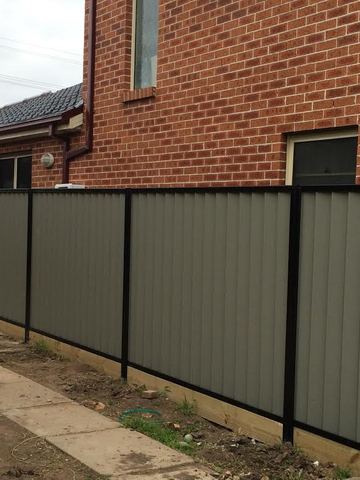 Mid grey Colorbond privacy fence running beside a brick house
