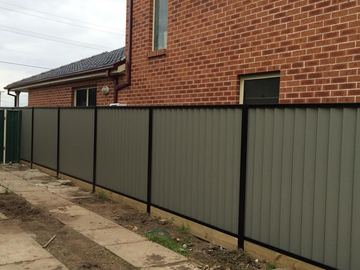 Mid grey Colorbond privacy fence running beside a brick house
