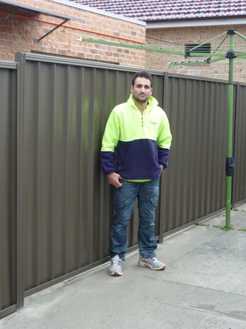 Mid grey Colorbond privacy fence beside a rotary clothesline with an installer standing in front