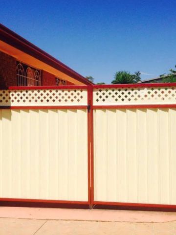 Charcoal double gate leaves topped with a narrow lattice panel between brick pillars.