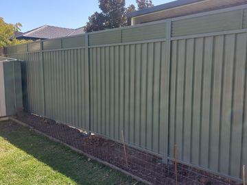 Mid grey Colorbond privacy fence standing across a garden bed