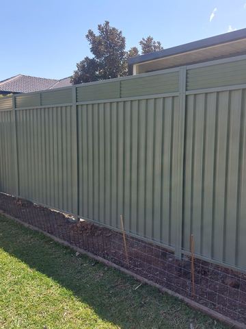 Mid grey Colorbond privacy fence standing across a garden bed