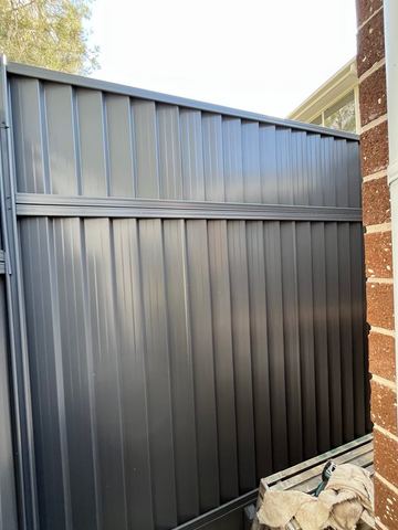Close view of mid grey Colorbond sheets returning to a brick house wall