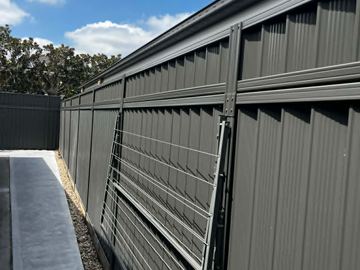 Charcoal Colorbond fence with a slatted screen bay along a paved side path