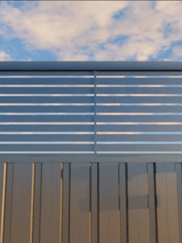 Close view of a charcoal Colorbond fence with a horizontal louvre topper