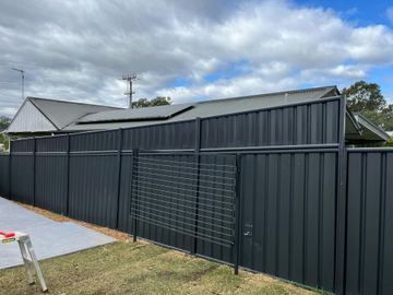 Charcoal Colorbond shed wall with a matching mesh pedestrian gate on a concrete pad